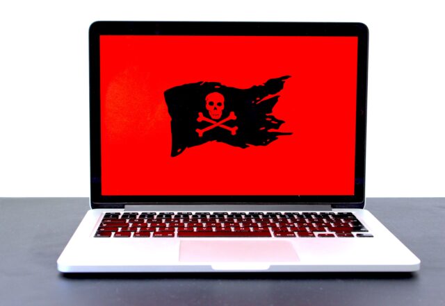 laptop with red screen and black flag with a skull
